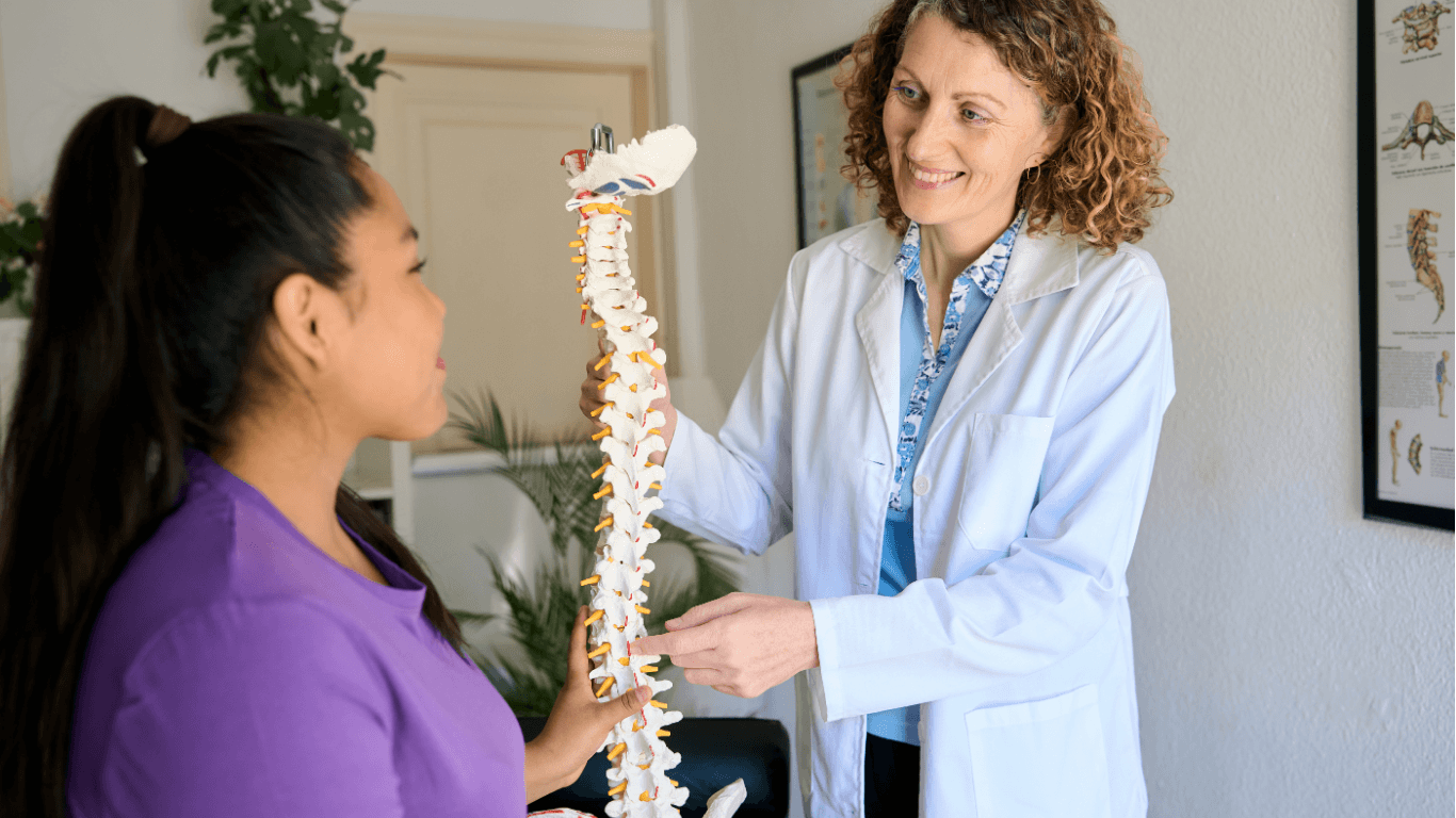 My Back Hurts Chiropractor explaining spinal health and back pain using a spine model during a patient consultation
