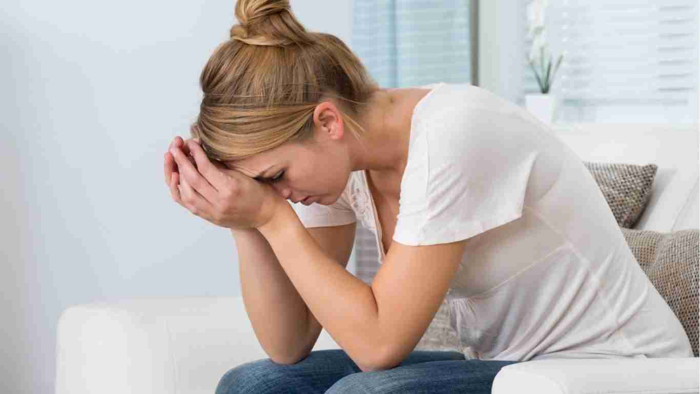 Busy Life Pain Relief Stress & Posture Solutions – female sitting on the couch with head in hands looking overwhelmed Busy Life Pain Relief: Stress & Posture Solutions - female sitting on the couch with head in hands looking overwhelmed