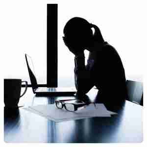 Busy Life Pain Relief: Stress & Posture Solutions - female with her head in her hands sitting in front of laptop in the dark still at work looking overwhelmed