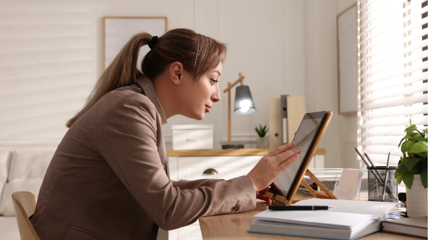 5 Simple Ways to Fix Spine Trouble - female with poor posture leaning forward at her desk working on a tablet