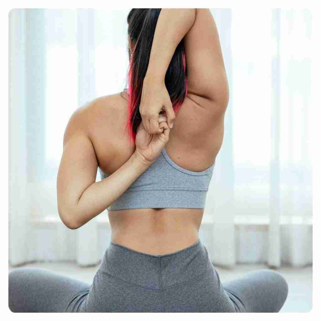 Benefits of Chiropractic Adjustments - female with sitting and arms linked behind her back 