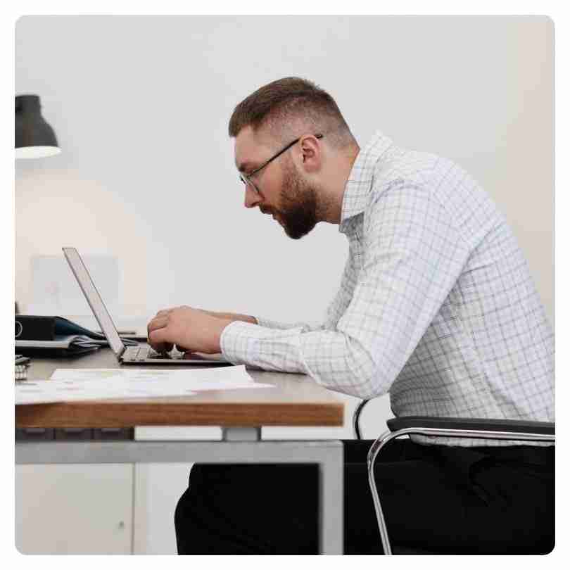 Man leaning forward over laptop showing poor posture and forward head position demonstrating the need for Tech Neck Treatment